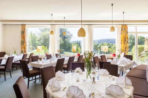 a restaurant with white tables and chairs and windows at Hotel Schwarzwald Freudenstadt in Freudenstadt