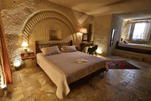 ギョレメにあるオスマンベイ ケイヴ ハウスの石造りの部屋に大型ベッドが備わるベッドルーム1室