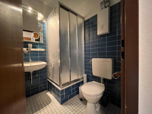 bagno piastrellato blu con servizi igienici e lavandino di Offline 51 City Apartments a Dusseldorf