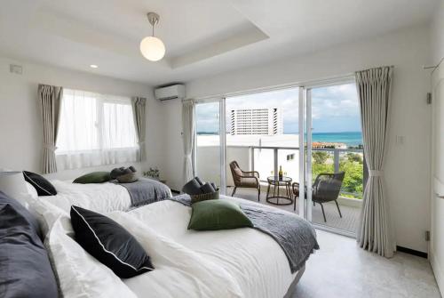 two beds in a bedroom with a view of the ocean at オーシャンビューFORTUNA YAKA Ace 12名対応 海まで徒歩 シャワールーム 2 BBQ OK in Kin