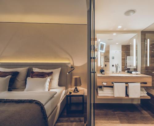 a bedroom with a bed and a bathroom with a sink at Elizabeth Arthotel Adults Only in Ischgl