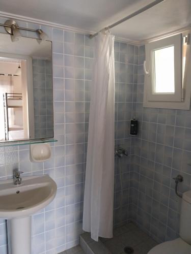 a bathroom with a sink and a shower curtain at Aggeliki Apartments in Nikiana