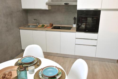 a kitchen with white cabinets and a table with chairs at el'Gio Feel at Home in Pordenone