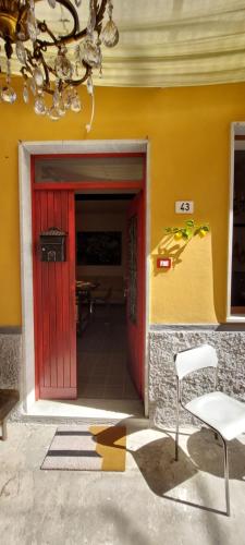 a red door on a yellow building with a chair at Moderno appartamento vista mare, con parcheggio privato in Portovenere