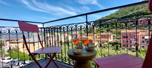 a balcony with two glasses of wine and two chairs at Moderno appartamento vista mare, con parcheggio privato in Portovenere
