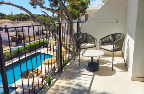 a balcony with two chairs and a table and a pool at Hotel Santanyi Port in Cala Figuera