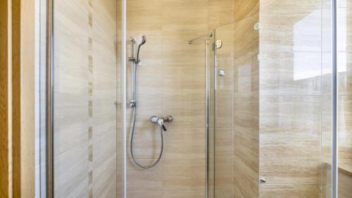 una ducha con puerta de cristal en un baño en Apartamenty PIAMOLA Powstańców Warszawy, en Stegna