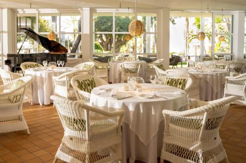 a restaurant with white tables and chairs and a piano at Melia Cala d'Or Boutique Hotel in Cala d´Or