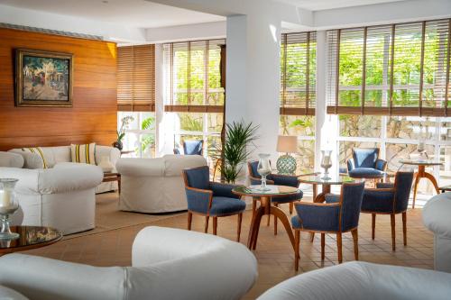 a living room with white furniture and tables and windows at Melia Cala d'Or Boutique Hotel in Cala d´Or