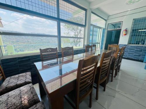 a dining room with a table and chairs and windows at PINAK HOMESTAY in Almora