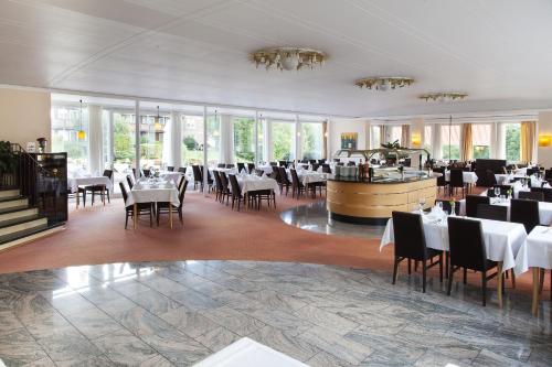 a dining room with tables and chairs and windows at Hotel Schwarzwald Freudenstadt in Freudenstadt