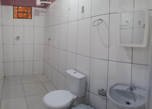 a white bathroom with a toilet and a sink at MACEDO HOSPEDAGEM in Mateiros