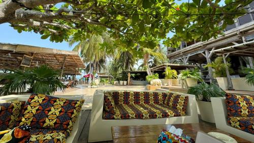 a patio with two couches and trees and plants at Hotel Coucoue Lodge in Assinie