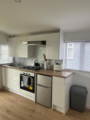 a kitchen with white cabinets and a stove top oven at The Cosy Summer House in Leysdown-on-Sea
