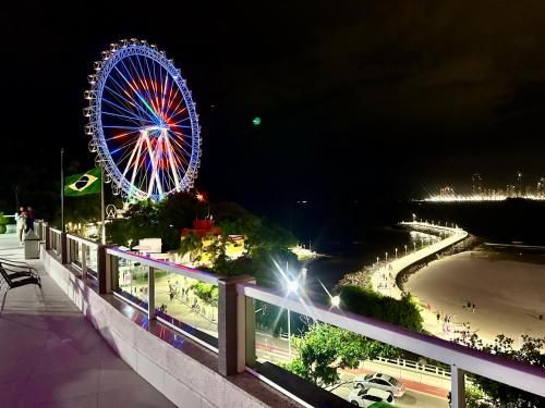 uma roda gigante e uma praia à noite em Studio Pé na Areia II em Balneário Camboriú