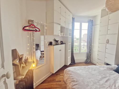 une chambre blanche avec un lit et une fenêtre dans l'établissement Charmant appartement à 10 mn de Paris, à Maisons-Alfort