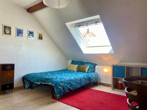 a bedroom with a blue bed and a skylight at Maison proximité Strasbourg centre in Schiltigheim