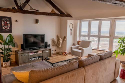 a living room with a couch and a television at Duplex atypique dans la cité médiévale in Laon