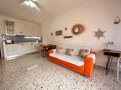 un salon avec un canapé orange et une cuisine dans l'établissement Cosy 2 pièces au calme avec balcon dans le centre ville, à Menton