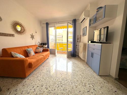 un salon avec un canapé orange et une télévision dans l'établissement Cosy 2 pièces au calme avec balcon dans le centre ville, à Menton