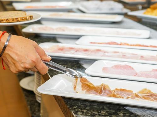a person is cutting meat on a plate at Hotel Pradillo Conil in Conil de la Frontera
