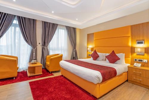 um quarto de hotel com uma cama e duas cadeiras em Watercress Hotels and Event em Ikeja