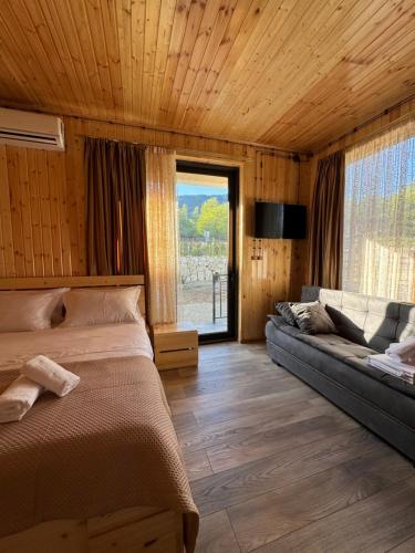 1 dormitorio con cama, sofá y ventana en Cottage ,,Okatsia” ოკაციას კოტეჯები en Gordi
