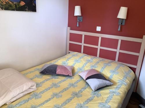 une chambre avec un lit avec deux oreillers dessus dans l'établissement Joli meublé T2 au Cap Esterel vue Esterel et mer, à Agay