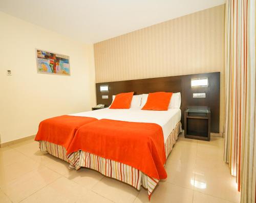 a bedroom with a large bed with an orange blanket at Hotel Pradillo Conil in Conil de la Frontera