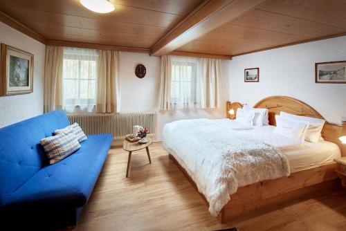 1 dormitorio con 1 cama grande y 1 sofá azul en Pension Heilbad Burgwies, en Stuhlfelden