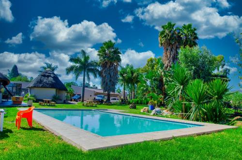 una piscina en un patio con palmeras en Riverstone Guest Lodge en Harare