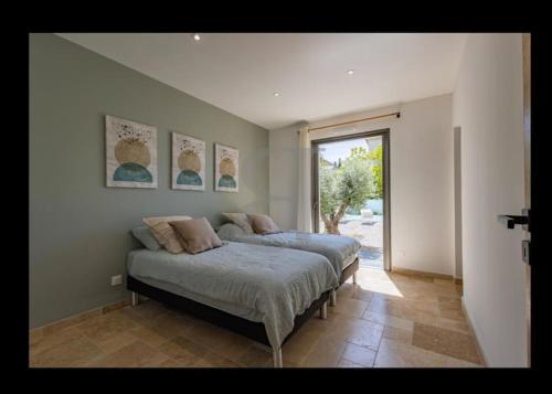une chambre avec deux lits et une grande fenêtre dans l'établissement Au pied des Alpilles villa 3 chambres, à Saint-Rémy-de-Provence