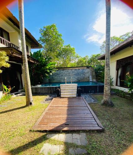 a wooden walkway in front of a house with a pool at Jimbaran Cozy Stay in Jimbaran
