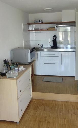 a kitchen with white cabinets and a microwave at Ferienwohnung Besenfelder in Notzingen