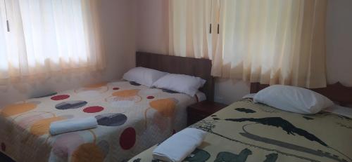 a bedroom with two beds with pillows and a blanket at Casa Vacacional Los Guayacanes in Baños