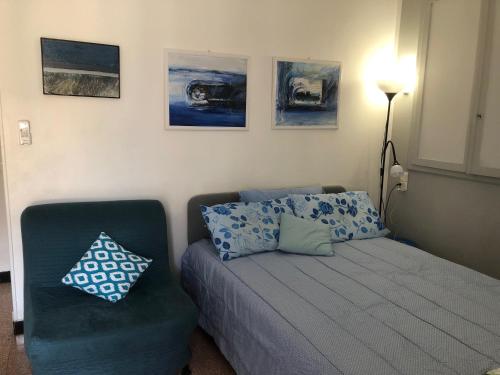 a bedroom with a bed and a chair and paintings at Welcome in the cozy blue nest pedestrian Menton in Menton