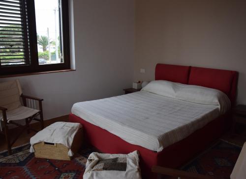 a bedroom with a bed and a chair and a window at Villa Marinella in Marinella di Selinunte