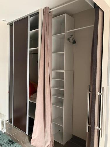 a walk in closet with a glass door and shelves at Appartement cosy tout équipé et parking couvert privé aux portes de Flers in Flers