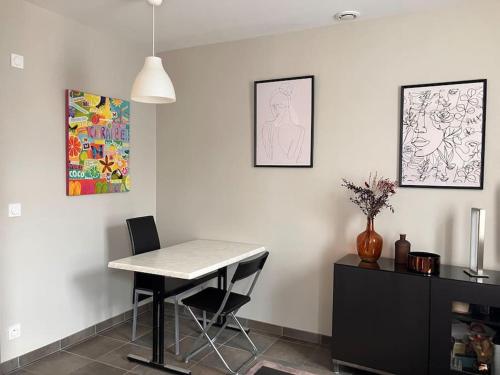 a dining room with a table and chairs and paintings at Appartement cosy tout équipé et parking couvert privé aux portes de Flers in Flers