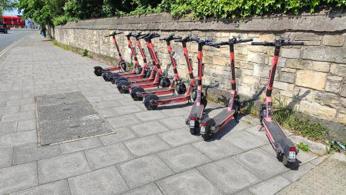 a row of scooters lined up against a stone wall at Town Centre House with parking in Cheltenham