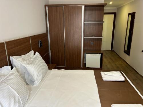 a bedroom with a white bed and a wooden cabinet at Gulluk Life Hotel in Gulluk