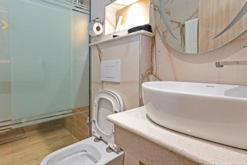 uma casa de banho com um lavatório, um WC e um espelho. em Watercress Hotels and Event em Ikeja