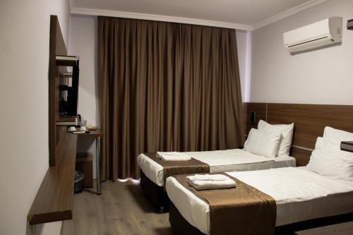 a hotel room with two beds and a television at Gulluk Life Hotel in Gulluk
