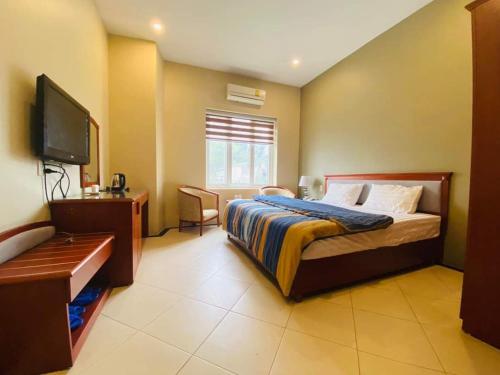 - une chambre avec un lit et une télévision à écran plat dans l'établissement Nam Phong Hotel & Coffee, à Cái Rồng