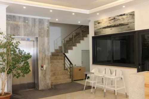 a living room with a staircase and white chairs at Gulluk Life Hotel in Gulluk