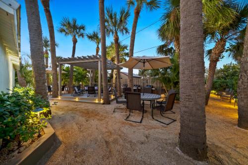 eine Terrasse mit einem Tisch, einem Sonnenschirm und Palmen in der Unterkunft Boutique Vacation Rental Complex At Beach in Cocoa Beach