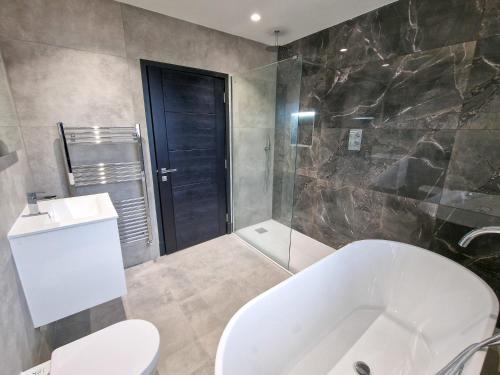 a bathroom with a tub and a toilet and a shower at Luxury 5* Didsbury Family Home in Manchester