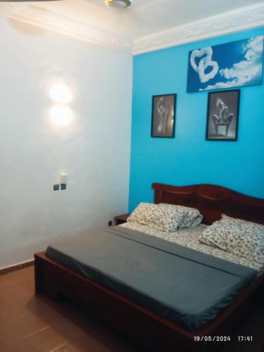 a bedroom with a bed with a blue wall at Richie club des rois in Agonkamè