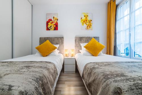 - 2 lits dans une chambre avec 2 oreillers jaunes dans l'établissement Disneyland Paris 6 Pers- WIFI - Disney TV Wifi, Parking, à Chessy