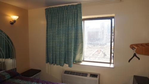 1 dormitorio con ventana, cama y ventilador en Flushing Motel, en Queens